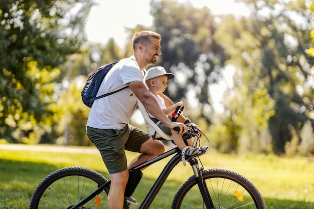 Ciclismo em família Pai e filho fazem uma pausa no ciclismo em um parque verde em um dia ensolarado de verão