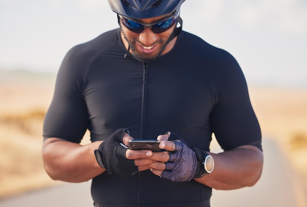 Ciclismo por telefone e natureza homem feliz em repouso parada no campo olhando para direção ou informações de mapa on-line Aplicativo de fitness de bate-papo móvel e ciclista de smartphone na estrada na pesquisa na internet com sorriso