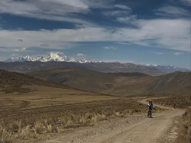 Ciclista acercándose en la ancha llanura por un camino escabroso