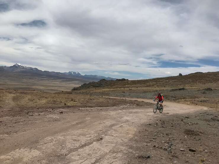 Ciclista acercándose a la conducción en la ancha llanura por un camino escabroso