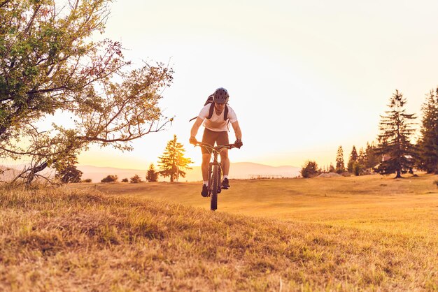 Un ciclista anda en bicicleta por caminos forestales al atardecer