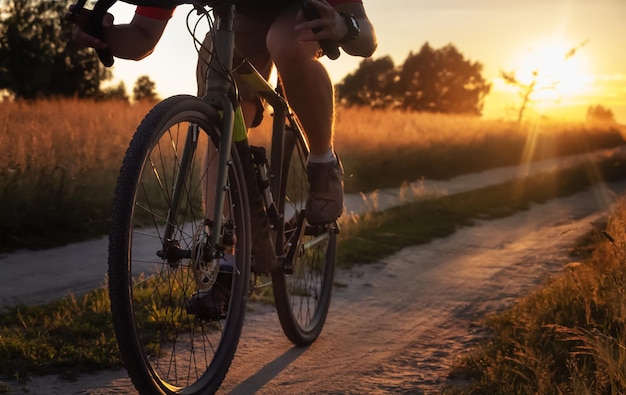 Ciclista anda de bicicleta na estrada de terra do campo