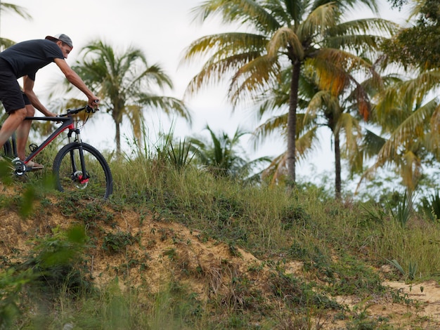 Ciclista andando de bicicleta na floresta tropical de trilha de montanha.