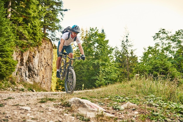 Ciclista andando de bicicleta na trilha na floresta Homem andando de bicicleta na trilha de enduro Motivação e inspiração de fitness esportivo Conceito de esporte extremo Foco seletivo