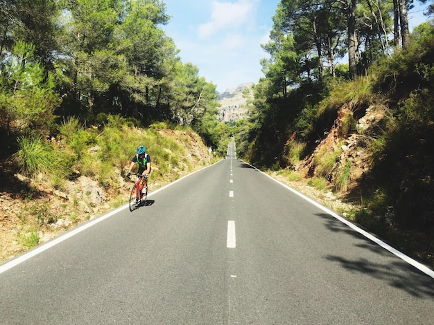 Foto ciclista andando na estrada durante um dia ensolarado