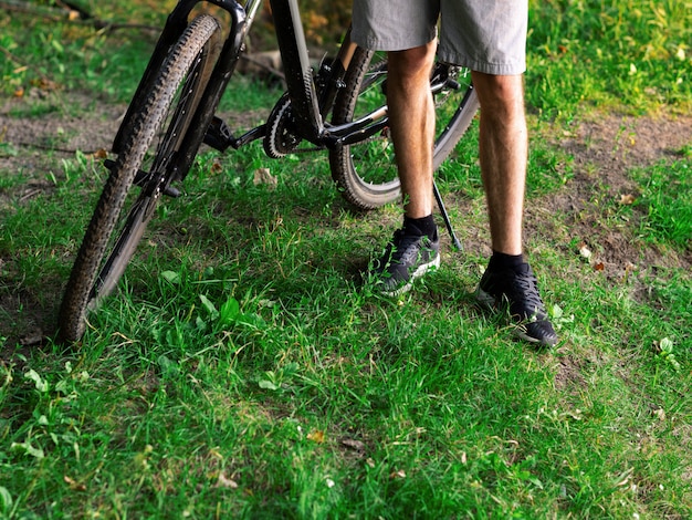 Ciclista ao lado da moto na floresta verde verão ao pôr do sol close-up