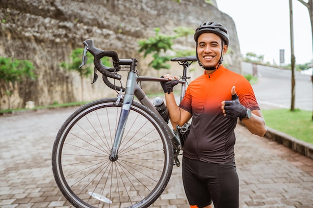 Ciclista asiática mostrando o polegar para cima e sorrindo para a câmera