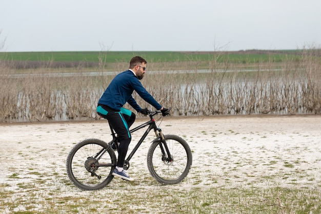Ciclista en bicicleta de montaña en una playa salada sobre un fondo de juncos y un lago