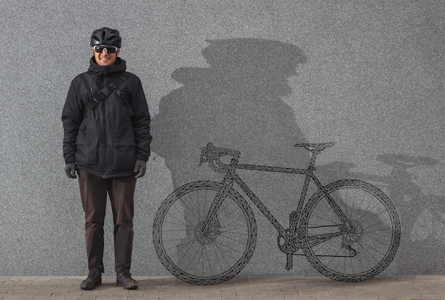 Ciclista con una bicicleta pintada junto a la pared