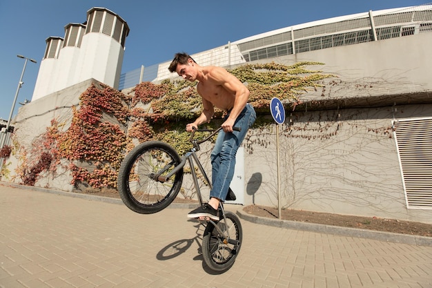 Foto ciclista de bmx adolescente está realizando trucos en el parque