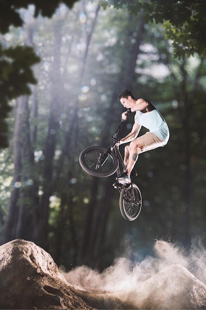 Ciclista de bmx engañando en las colinas del bosque