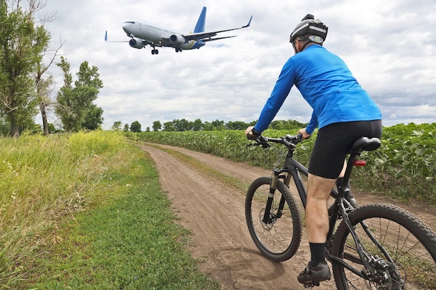 Ciclista cabalgando por un sendero en el de volar un avión de pasajeros