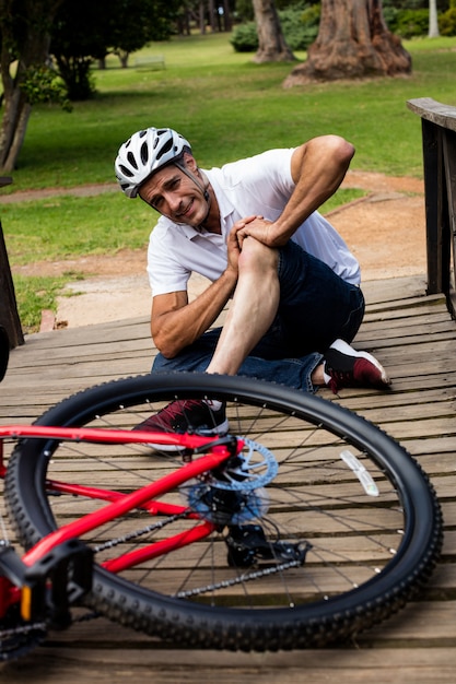 Ciclista caído, segurando o joelho machucado