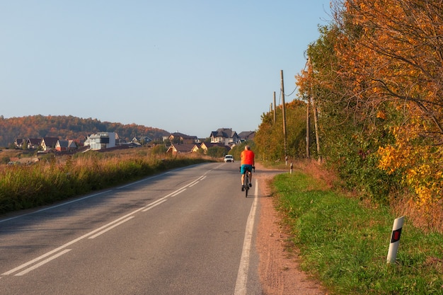 Un ciclista en una carretera de otoño de campo.