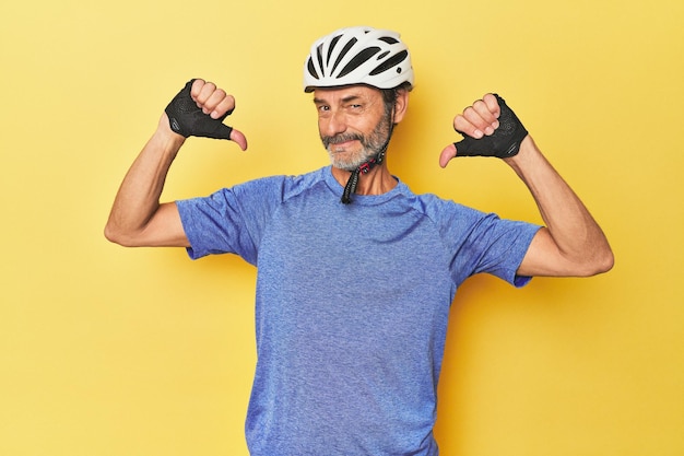 Un ciclista con casco en un estudio amarillo se siente orgulloso y seguro de sí mismo, un ejemplo a seguir