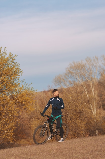 Ciclista cavalga pela floresta de outono e parque