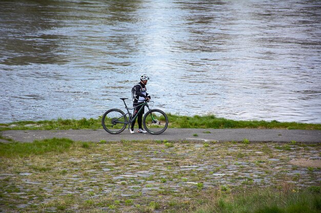 El ciclista se para cerca del río por la mañana.