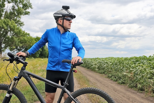 Ciclista com bicicleta em pé no caminho de campo