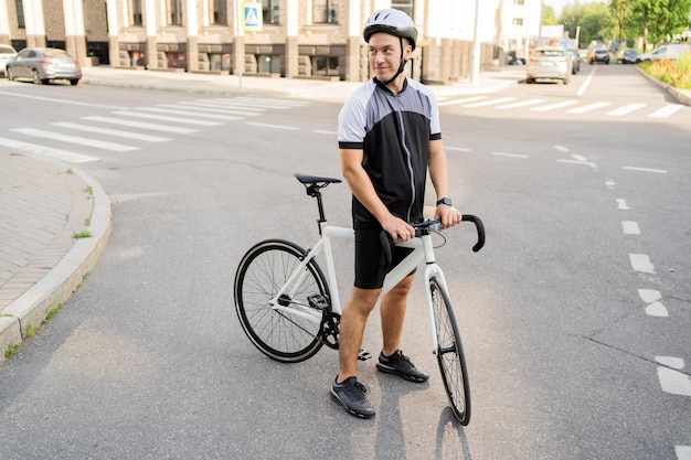 Ciclista com capacete e roupas esportivas com uma bicicleta fixie em uma rua urbana pronta para um ambiente sustentável