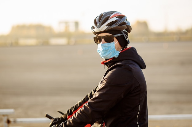 Ciclista durante la cuarentena con casco y máscara