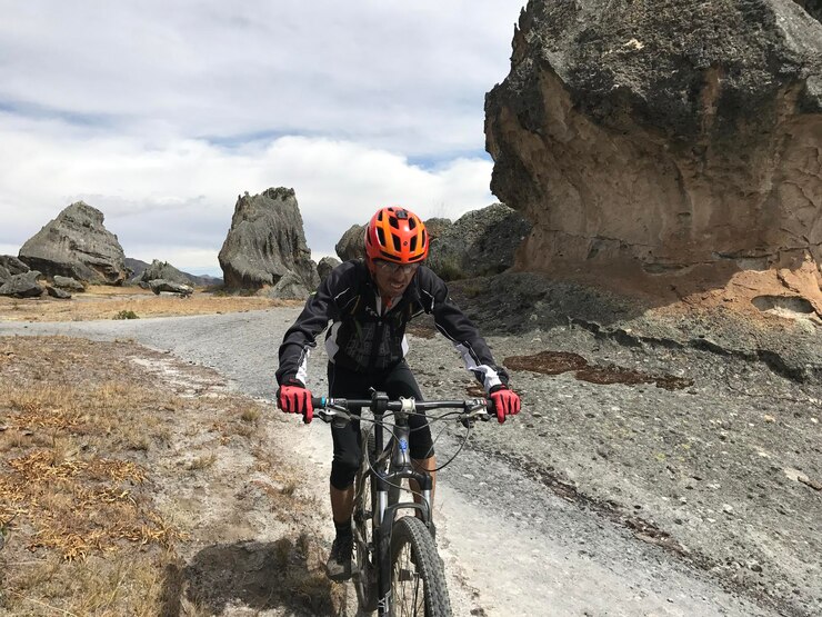 Ciclista cuesta arriba por un camino entre rocas gigantes