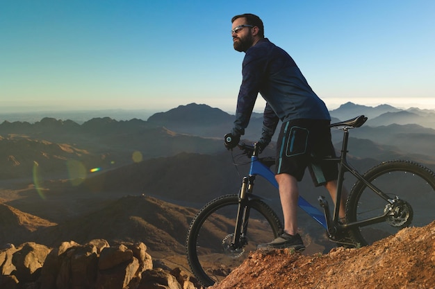 Ciclista de bermuda e malha em uma bicicleta moderna de carbono com suspensão a ar