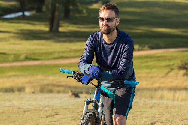 Ciclista de bermuda e malha em uma bicicleta moderna de carbono com suspensão a ar