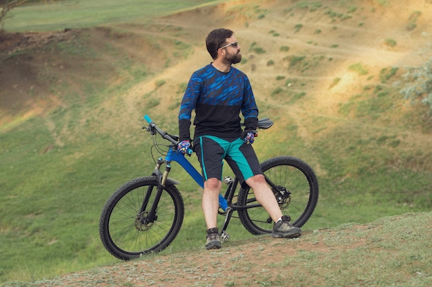 Ciclista de bermuda e malha em uma bicicleta moderna de carbono com suspensão a ar