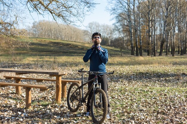 Ciclista de calça e jaqueta de lã em uma bicicleta de carbono com um garfo de suspensão a ar viaja off-road