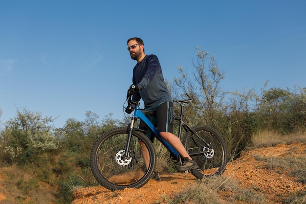 Ciclista de calça e jaqueta de lã em uma bicicleta moderna com suspensão pneumática viaja off-road