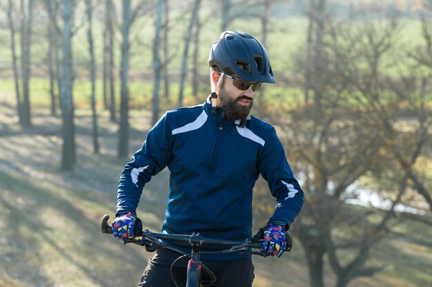 Ciclista de calça e jaqueta de lã em uma bicicleta moderna de carbono rígido em passeios offroad