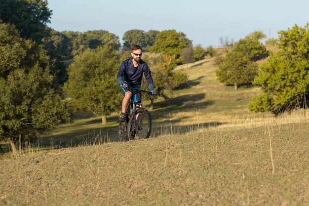 Ciclista de calça e jaqueta de lã em uma moderna bicicleta rígida de carbono com suspensão a ar.