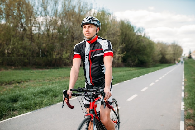 Ciclista de capacete e roupas esportivas em bicicleta esportiva. treino em ciclovia, ciclismo