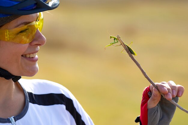 Ciclista de linda garota segurando um besouro mantis. Natureza e homem