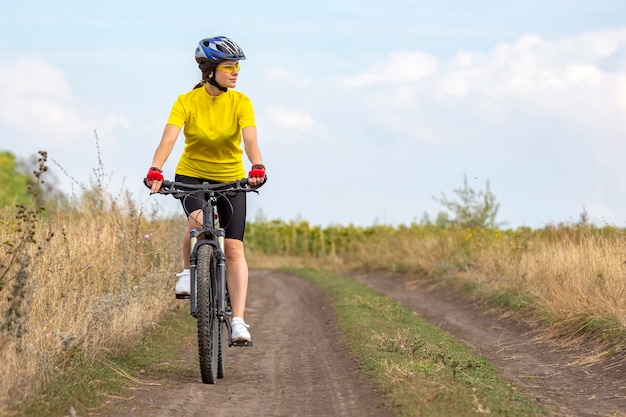Ciclista de mulher bonita e feliz anda de bicicleta na estrada na natureza. Estilo de vida saudável e esportes. Lazer e hobbies