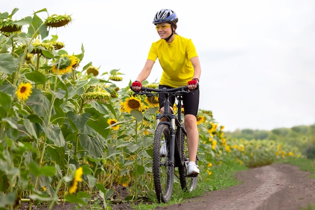 Ciclista de mulher bonita e feliz anda de bicicleta na estrada na natureza. Estilo de vida saudável e esportes. Lazer e hobbies