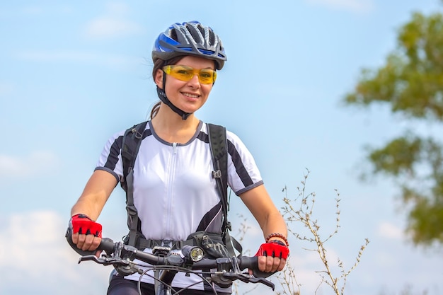 Ciclista de mulher bonita e feliz com uma bicicleta na natureza. Estilo de vida saudável e esportes. Lazer e hobbies