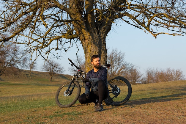 Ciclista de short e jersey em uma bicicleta de carbono com um garfo de suspensão a ar em um penhasco