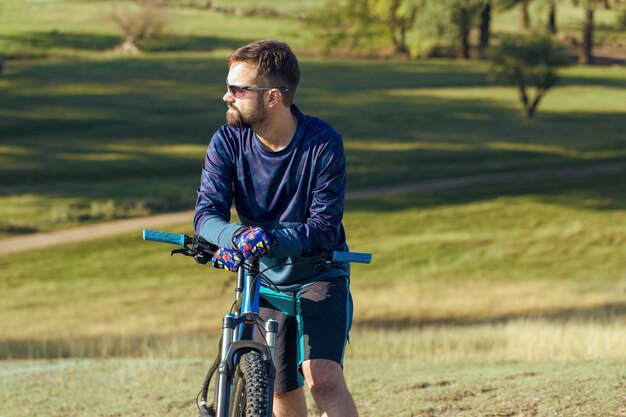 Ciclista de short e jersey em uma bicicleta moderna de carbono com um garfo de suspensão a ar em um penhasco