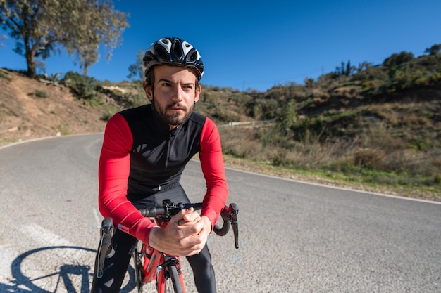 Foto el ciclista descansa su brazo en el manillar de la bicicleta en el camino de la montaña durante la mañana