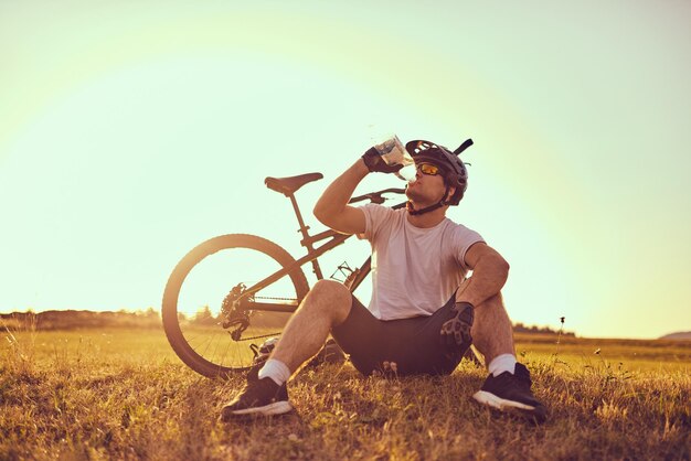 Ciclista descansando después de un extenuante paseo en bicicleta por caminos forestales. foto de alta calidad