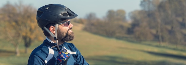 Ciclista em calças e jaqueta de lã em uma moderna bicicleta hardtail de carbono com um garfo de suspensão a ar O cara no topo da colina anda de bicicleta