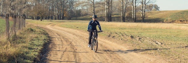 Ciclista em calças e jaqueta de lã em uma moderna bicicleta hardtail de carbono com um garfo de suspensão a ar passeios offroad