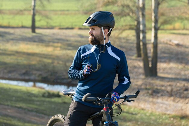 Ciclista em calças e jaqueta de lã em uma moderna bicicleta hardtail de carbono com um garfo de suspensão a ar