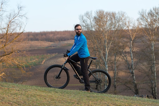 Ciclista em calças e jaqueta de lã em uma moderna bicicleta hardtail de carbono com um garfo de suspensão a ar