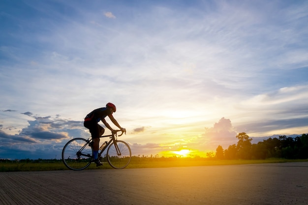 Ciclista em movimento no fundo belo pôr do sol com a silhueta. Ciclista no conceito de verão