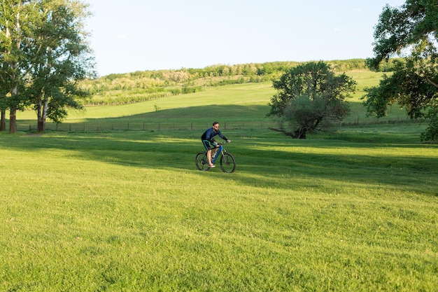 Ciclista em prados verdes em uma bela paisagem de noite de verão
