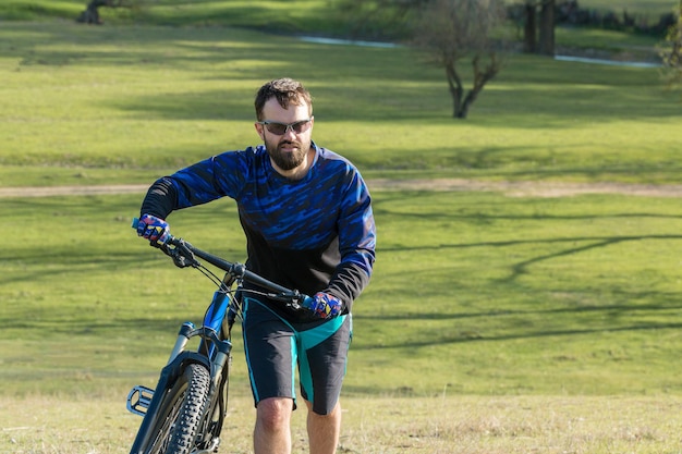 Ciclista em prados verdes em uma bela paisagem de noite de verão