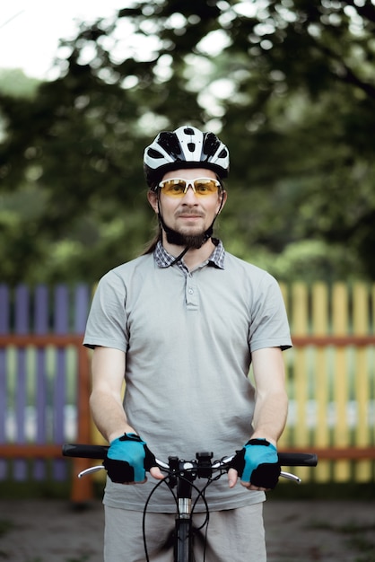 Ciclista em roupas esportivas e capacete fica na estrada no parque olhando para frente