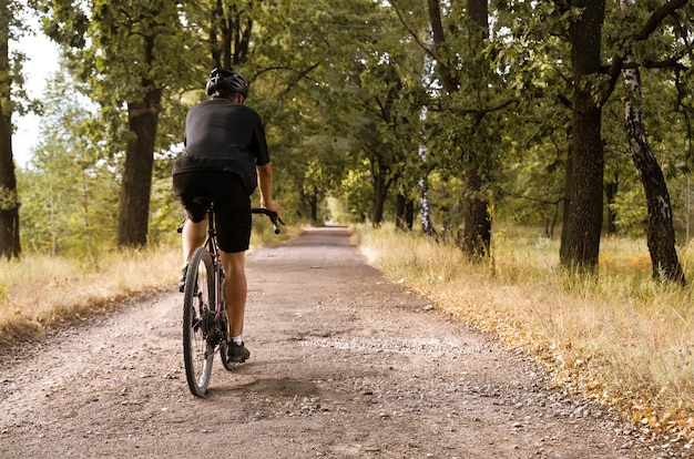 Ciclista em uma bicicleta de cascalho anda ao longo de uma estrada rural com poços. atividade esportiva ao ar livre.